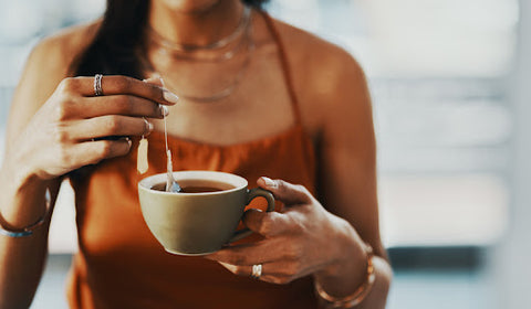 Woman steeping tea in a tea cup.