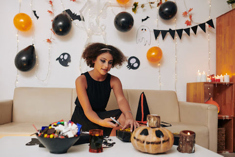 Woman wrapping halloween gift box with halloween decor background