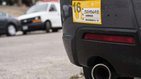 Yellow sticker parking permit on the bumper of a black car