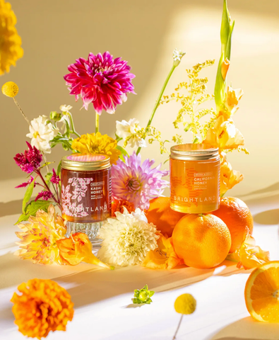 Two honey jars in a colorful flower and fruit display.