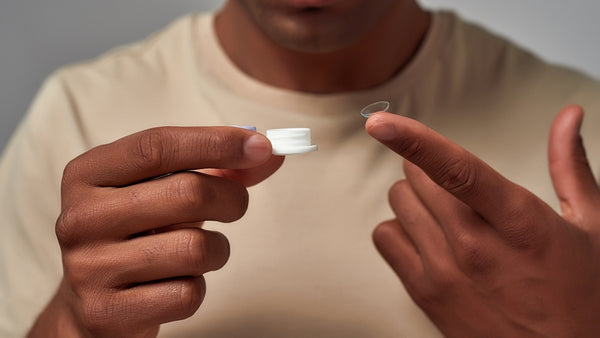 A man removes his contact lens from the contact lens solution