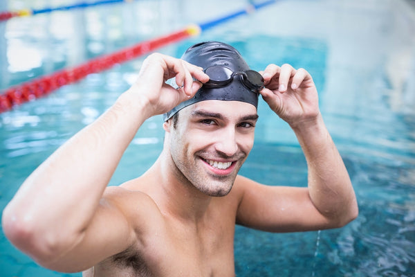 A swimmer puts on his goggles before getting into the pool