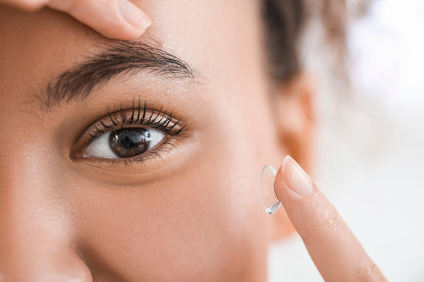 A woman gets ready to insert a contact lens into her eye