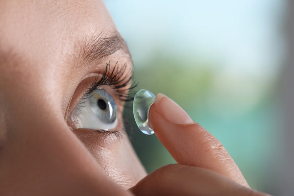 A woman looks up as she inserts a contact lens