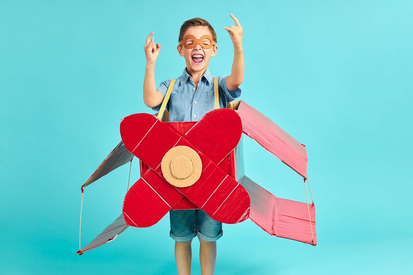 little boy wearing an aeroplane costume made from cardboard boxes