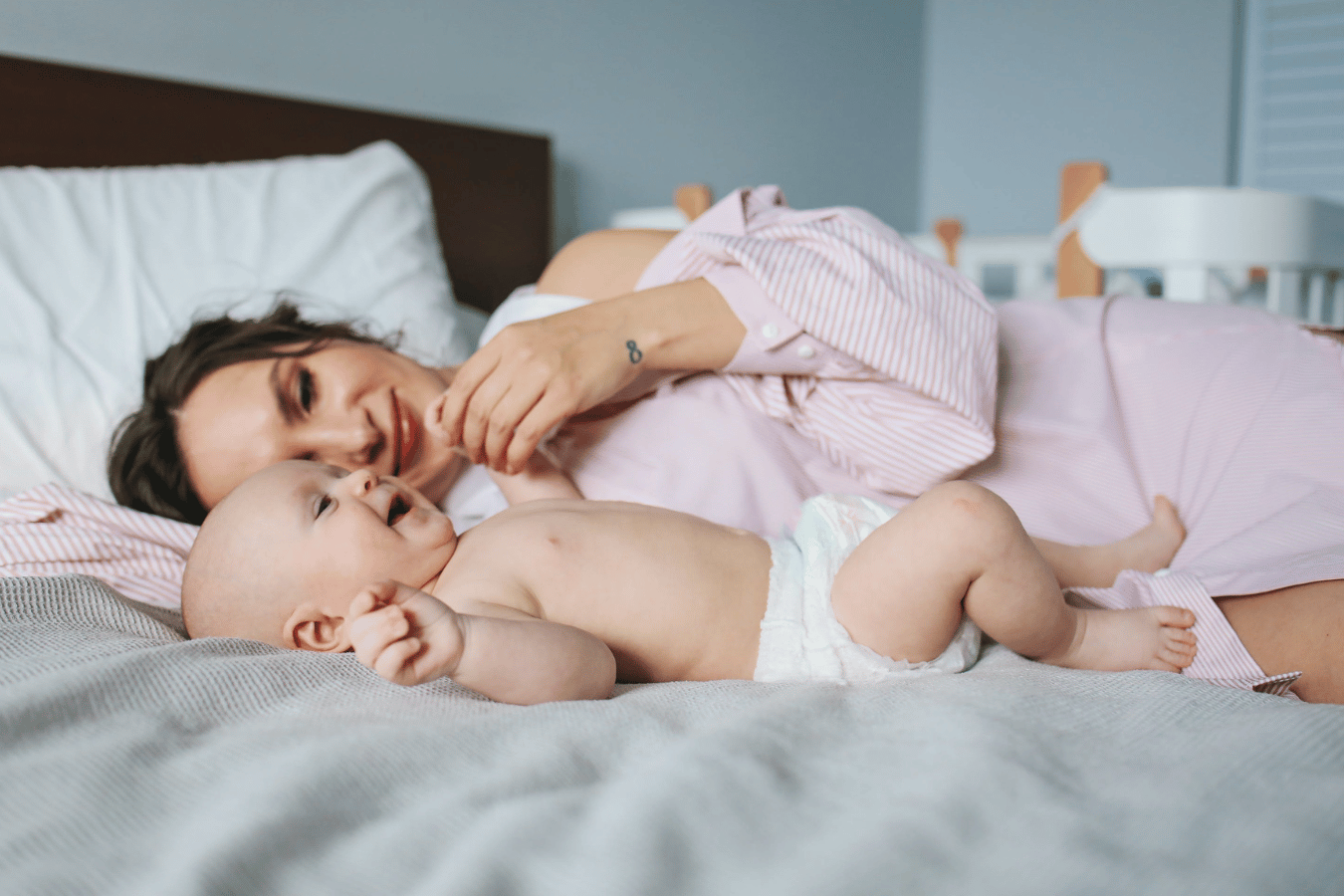 nipple pain while breastfeeding- mother and baby on bed- Mila's Keeper