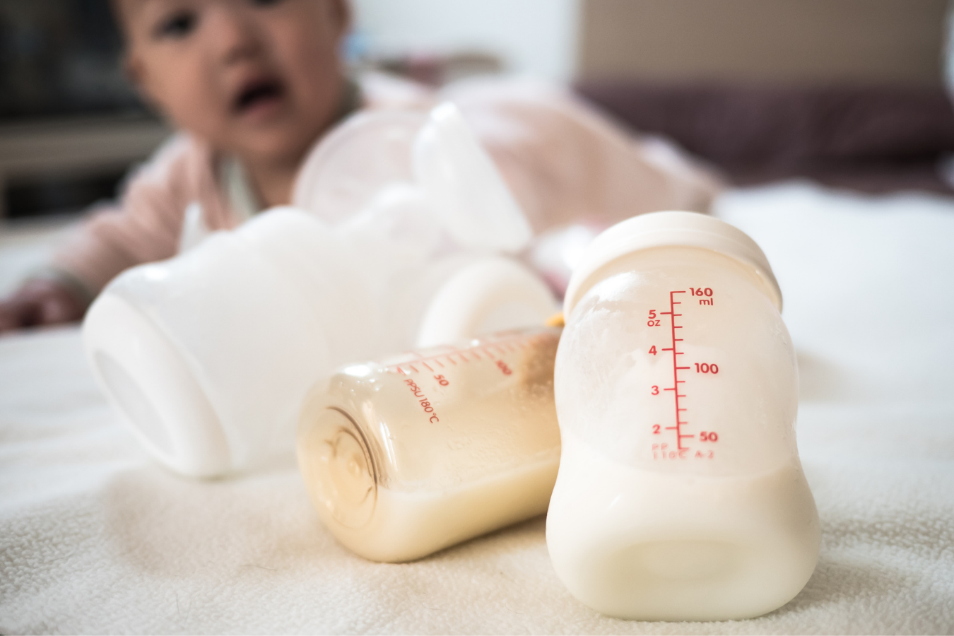 breast milk in bottles with baby in background