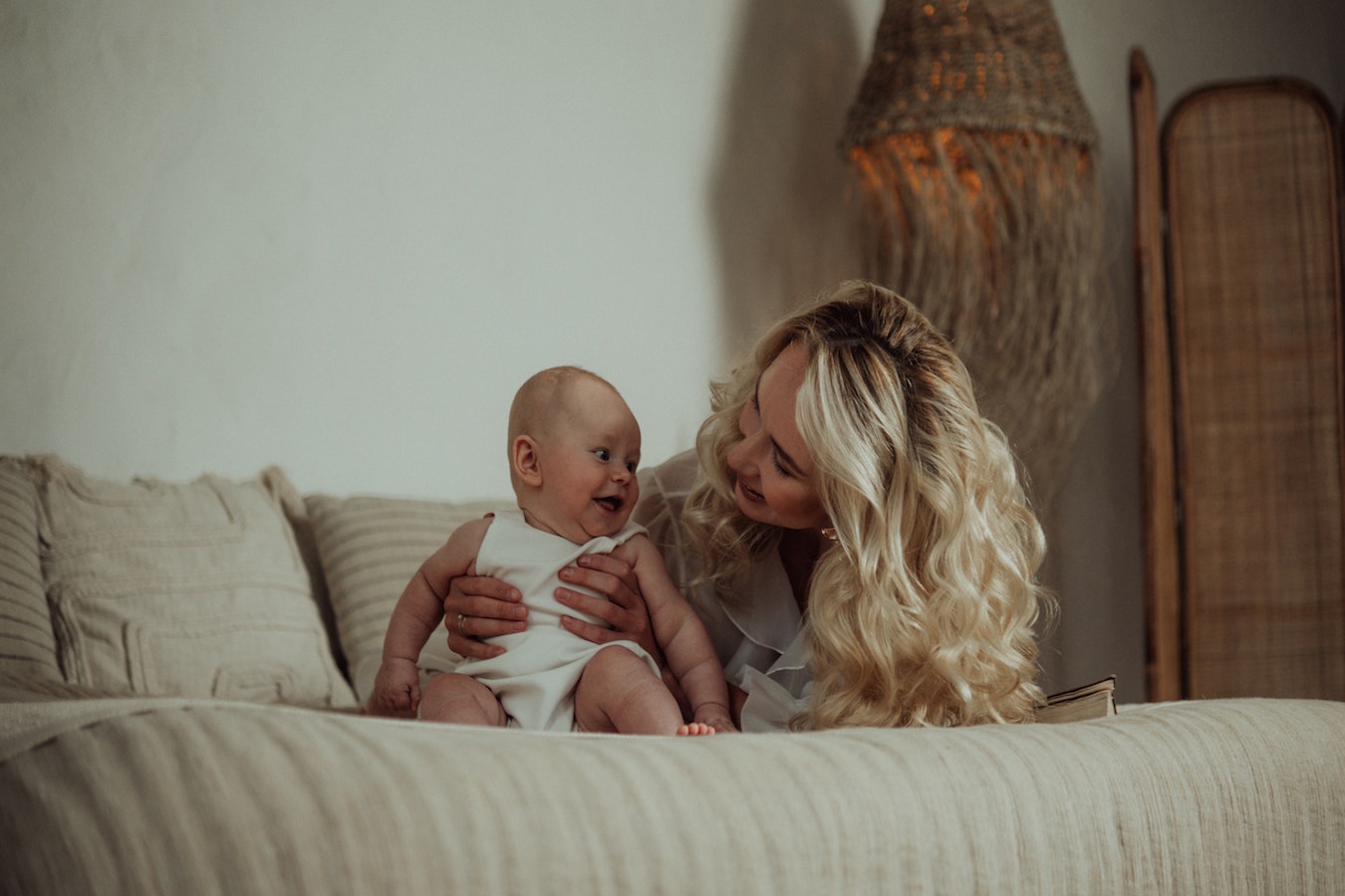 mom holding baby on bed-9 Reasons why you should speak with a lactation consultant- Mila's Keeper