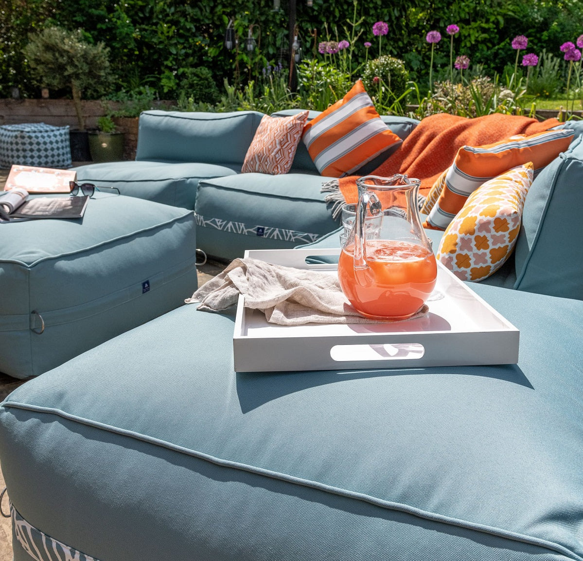 Garden sofa and ottoman in ocean blue, with bright orange weatherproof cushions