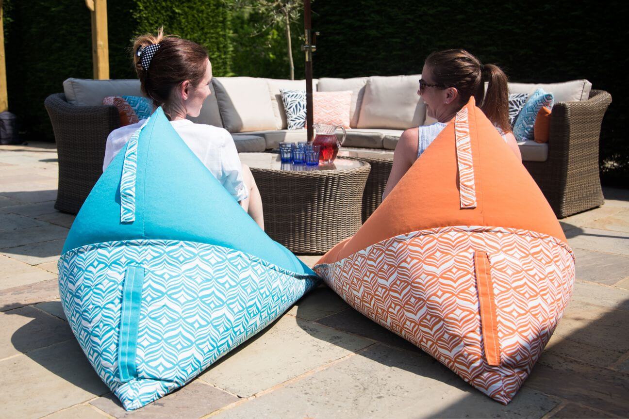 Two women sit talking and laughing on outdoor bean bags on the patio