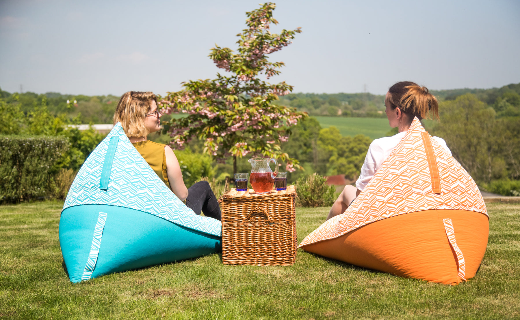 Two friends chat amiably from the comfort of garden bean bag chairs