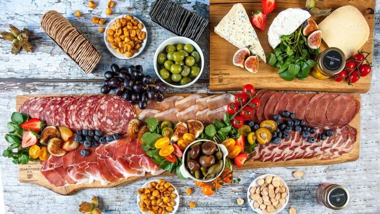 Cold meats, charcuterie, fruit, olives and crudites on a long wooden serving board