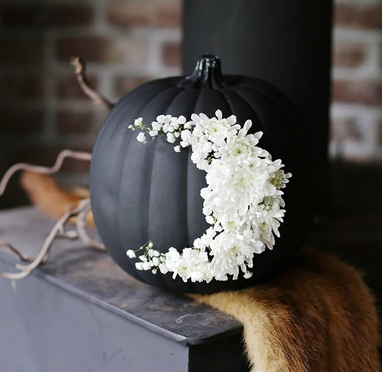 Pumpkin painted black with white floral moon is the centrepiece for a classy Halloween garden party