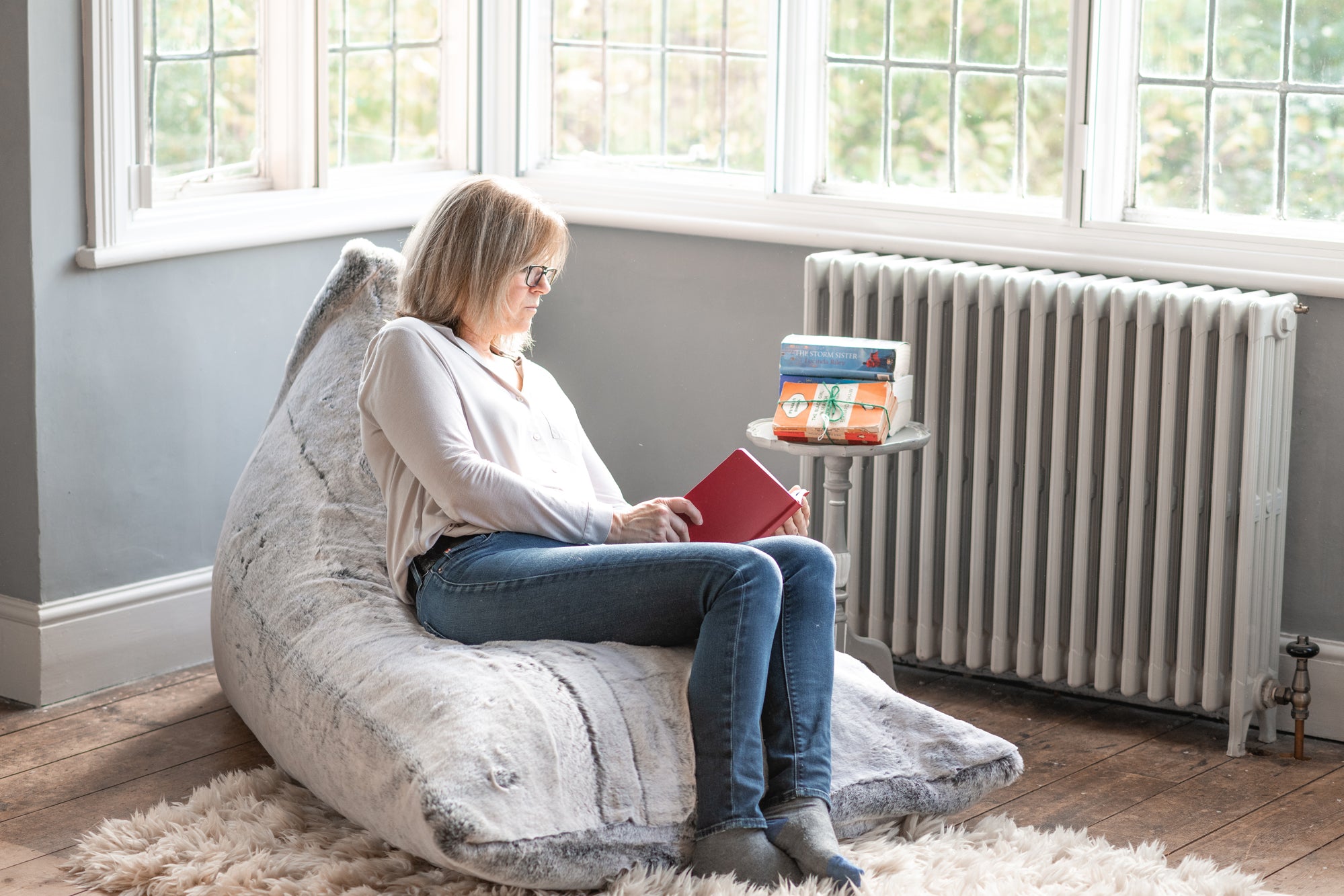 A snuggly faux fur bean bag in Alaska Fox is the cosiest reading corner for the woman snuggled into it with her pile of books
