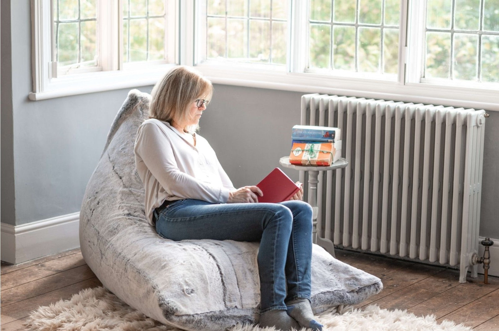 Someone reads a book in a cosy corner on a faux fur bean bag