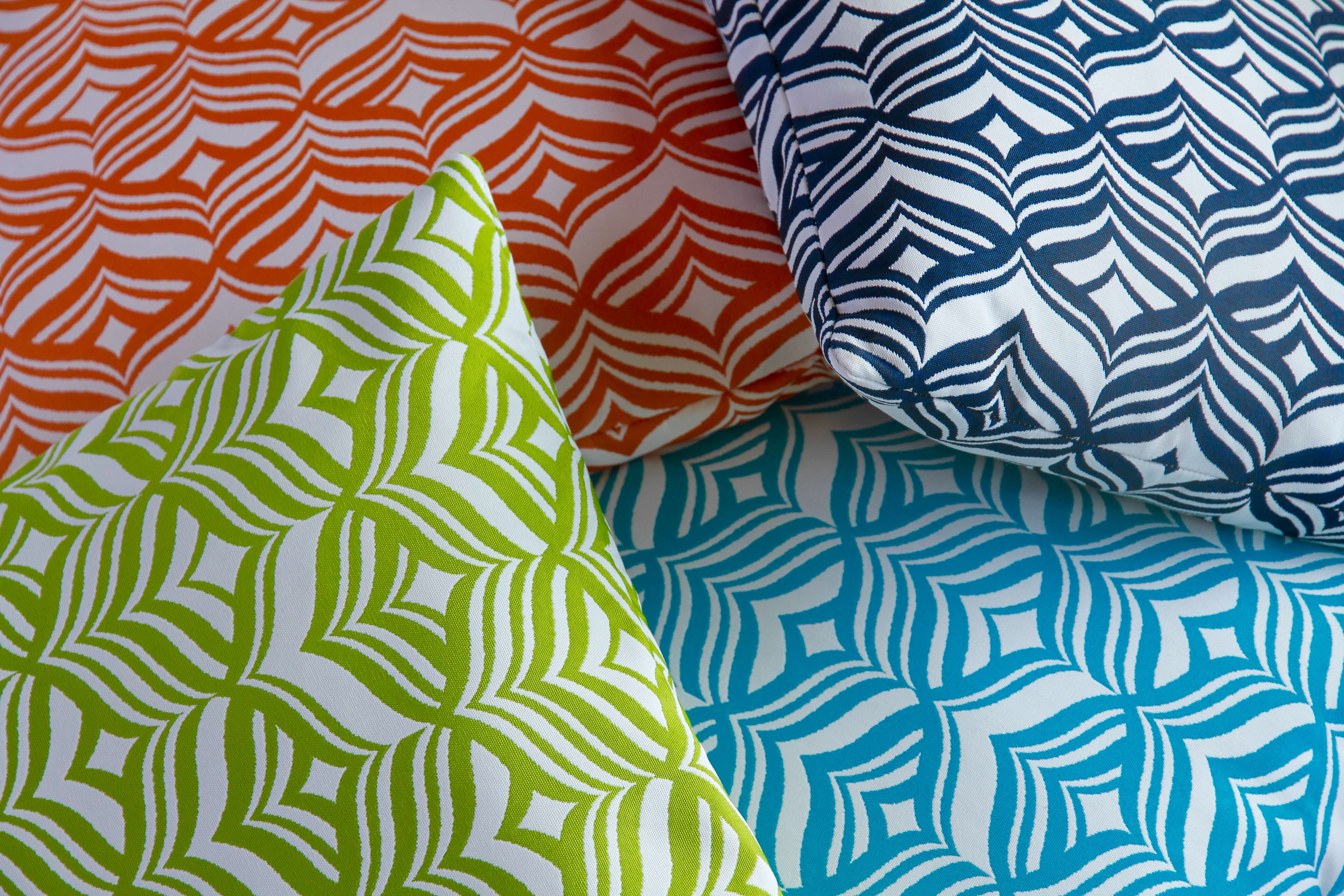Four Outdoor Cushions in patterned fabric of orange, turquoise, lime green and navy blue