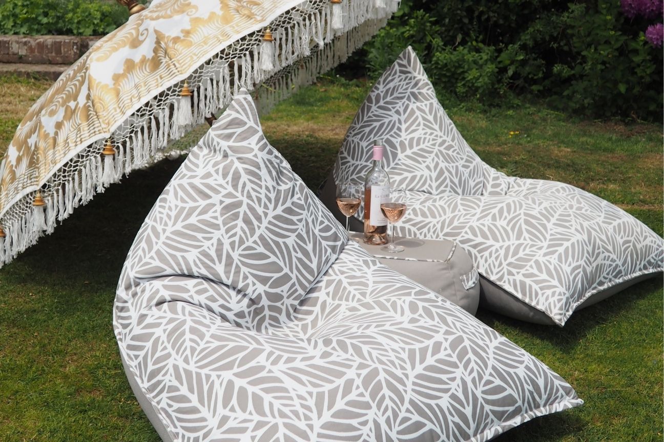 Two luxury outdoor loungers sit on the grass under a parasol