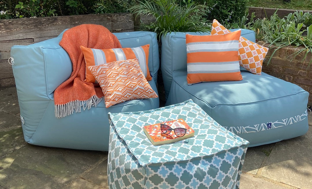 Garden sofa chairs and an outdoor pouffe decorated with orange cushions