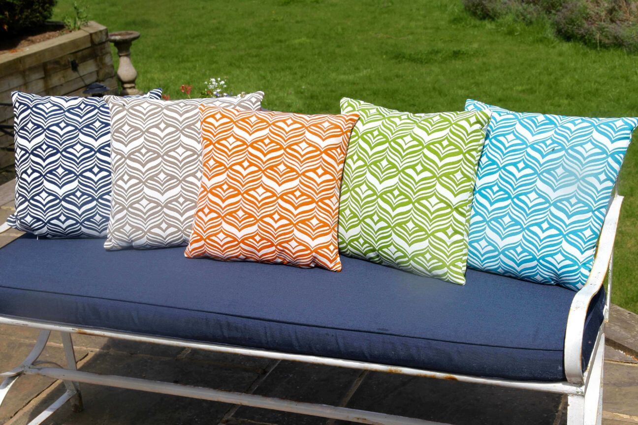 Five colourful patterned outdoor cushions on a metal garden bench
