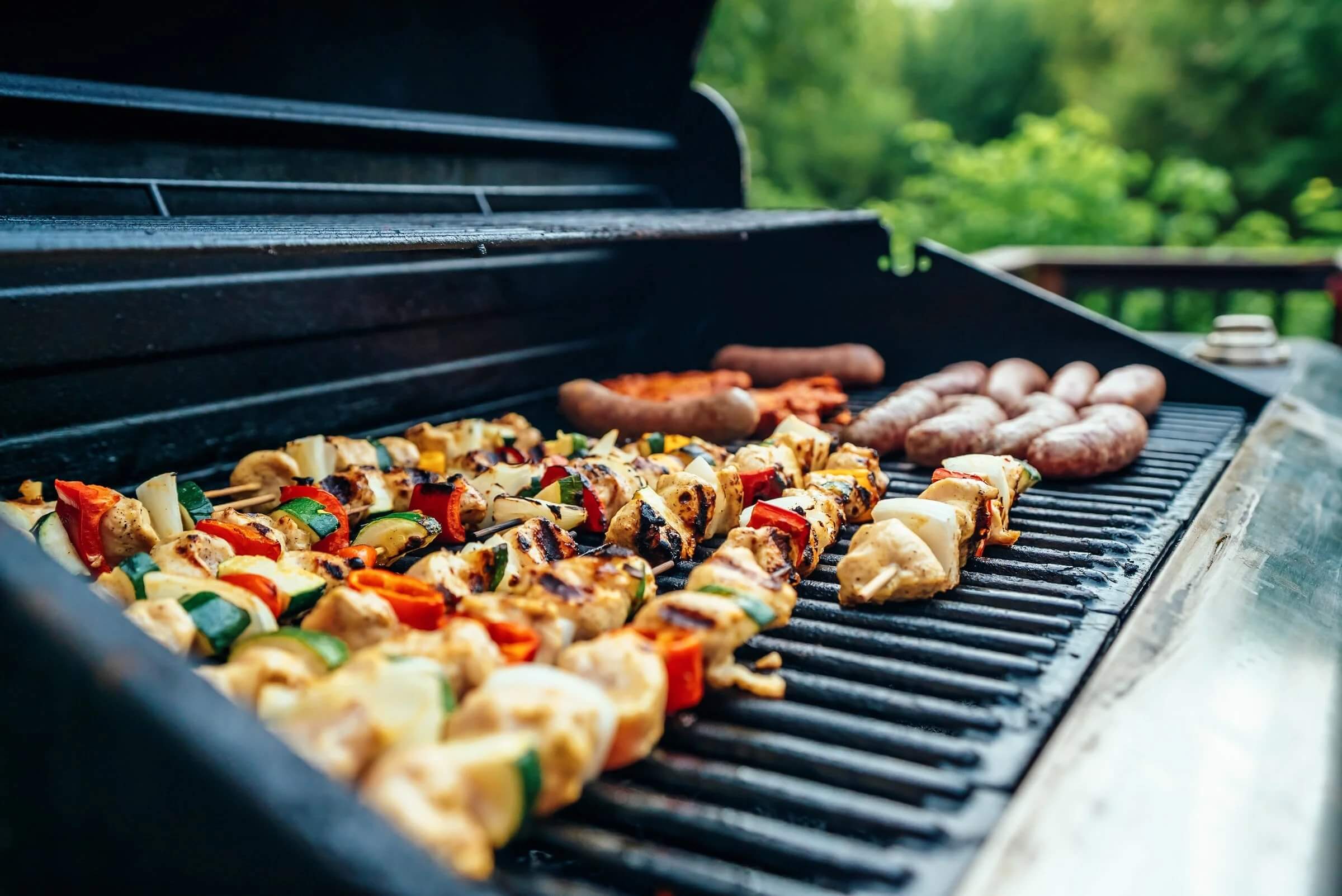 A sizzling BBQ with chicken kebabs and sausages cooking