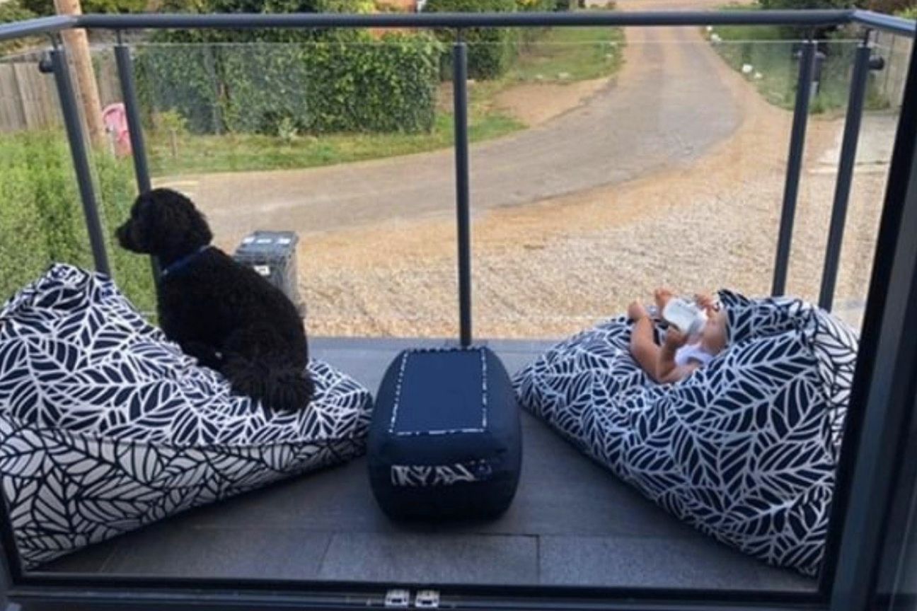 An Armadillo Sun customer photograph of two navy and white bean bag chairs. A baby sits on one drinking his milk, the other has a fluffy black dog sitting on it.