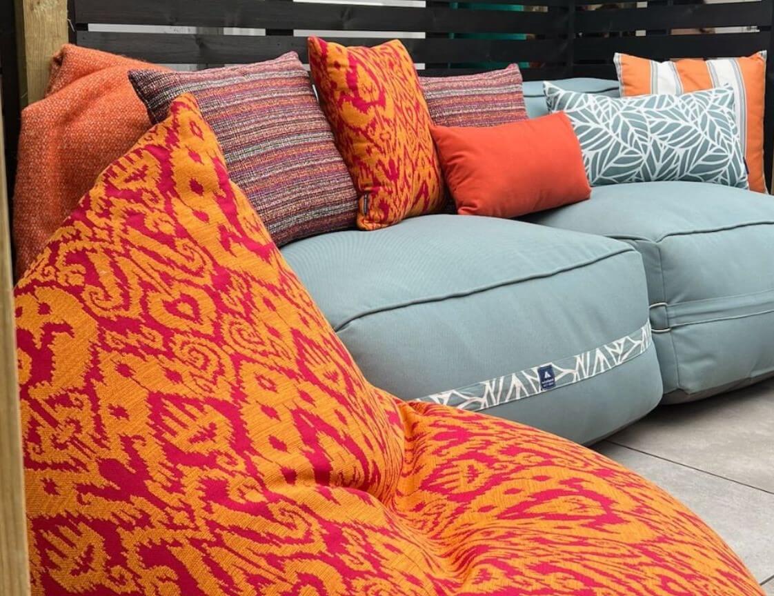 Comfy sofa next to a tropical-coloured orange and pink bean bag chair in a small outdoor space