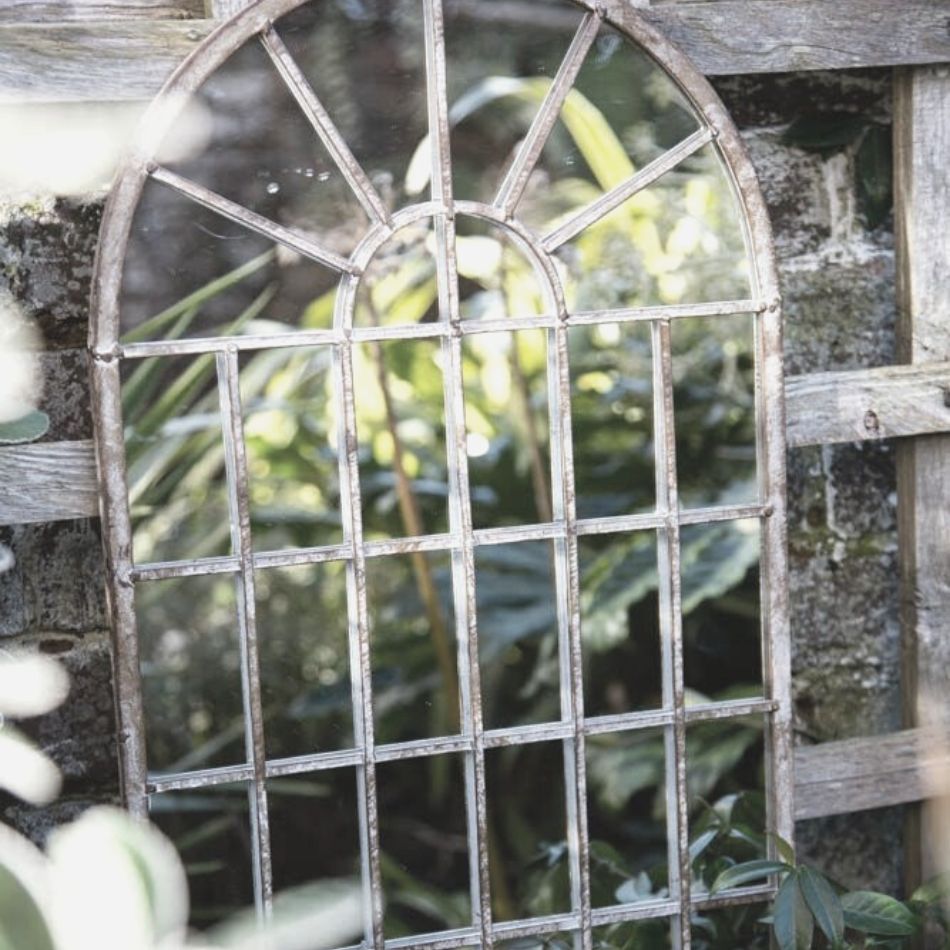 Classy antique-style outdoor mirror leans against a fence for a Halloween garden party
