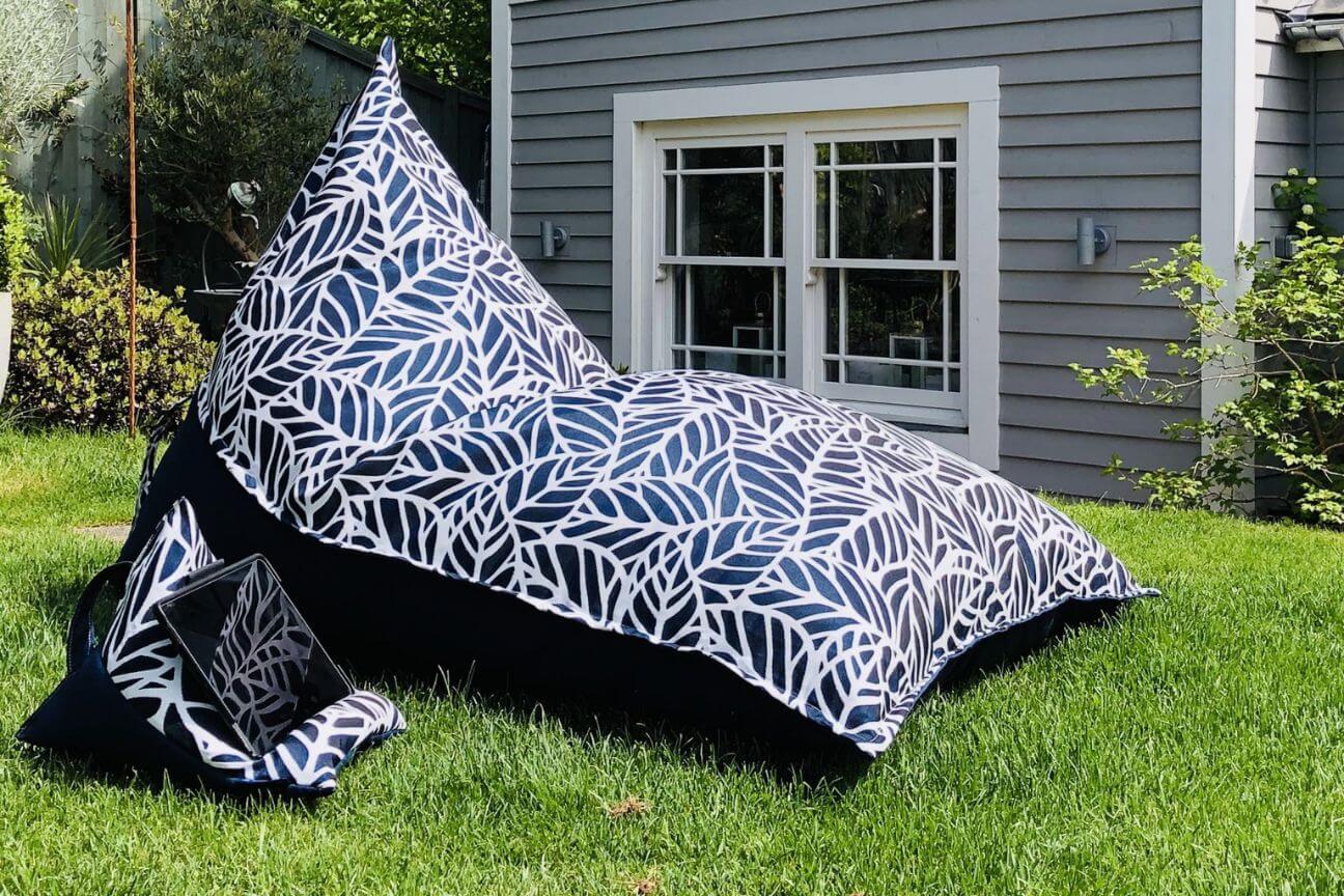 Navy blue bean bag chair on a green lush lawn