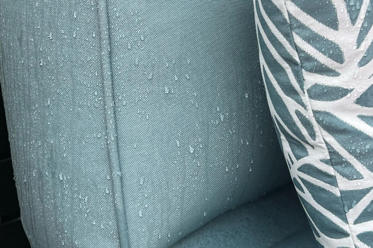 Water resistant fabric outdoor cushion and garden sofa with water beads from the rain rolling off it