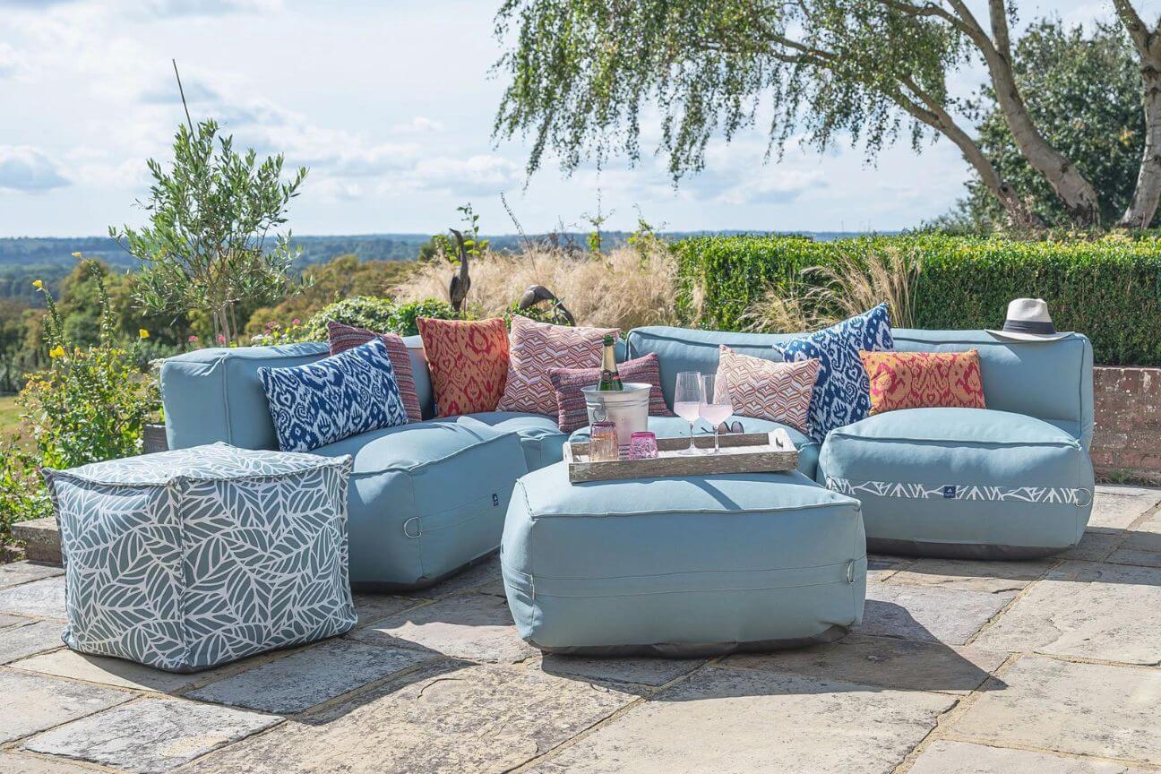 A cushioned outdoor sofa is ready for garden party guests on a sunny patio