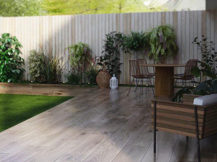 Outdoor patio tiled with wood-effect porcelain pavers used for a garden table and chairs and planters