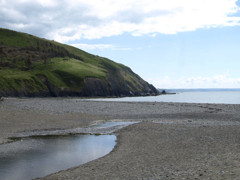 View of a welsh beach with sea in the far distance and welsh hills to the left