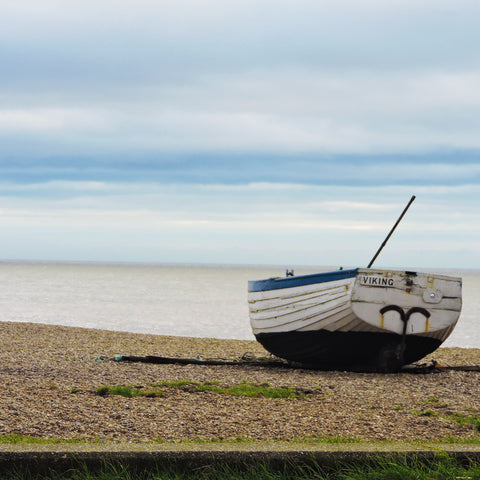 Boat on a pebble beach with sea in background 