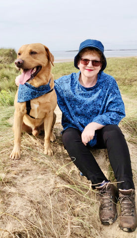Kim and her Labrador Leo wearing a blue print chambray shirt and bucket hat with matching collar, lead and bandana by the sea in Anglesey perfect for Twin With Your Dog Day  