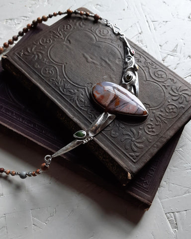 purple necklace on antique books