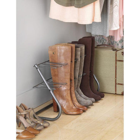 A pair of brown leather boots with boot trees inserted, standing upright in a cool, dry closet.