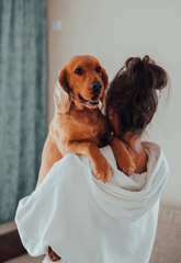 Woman cuddling dog on shoulder
