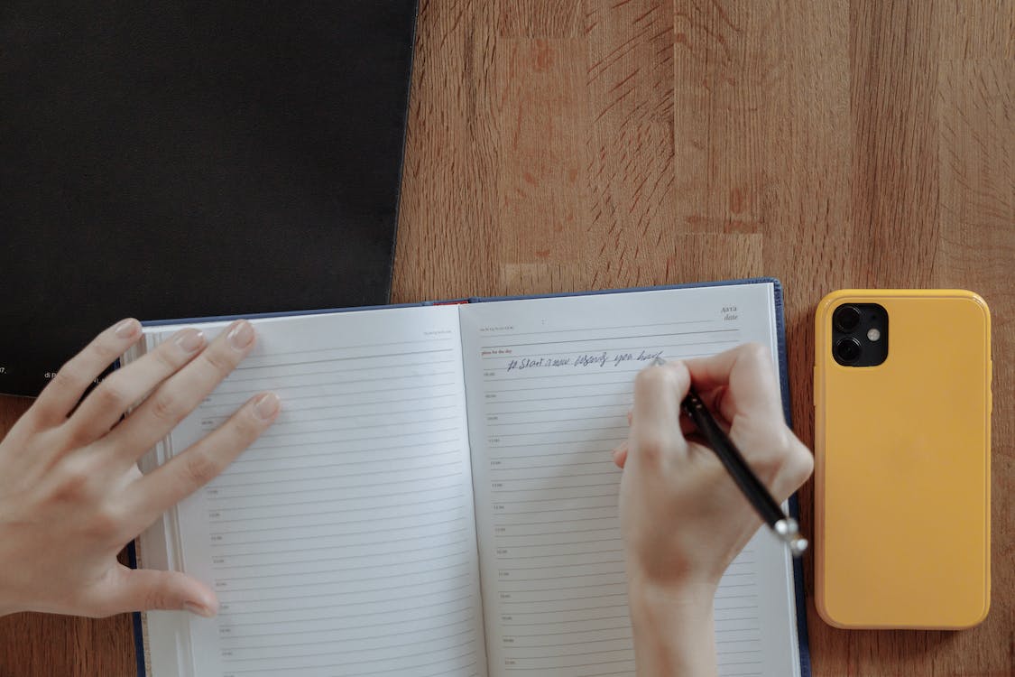 Person Writing on Notebook