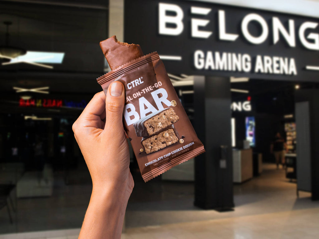 Hand holding chocolate chip cookie dough on the go bar outside belong gaming arena