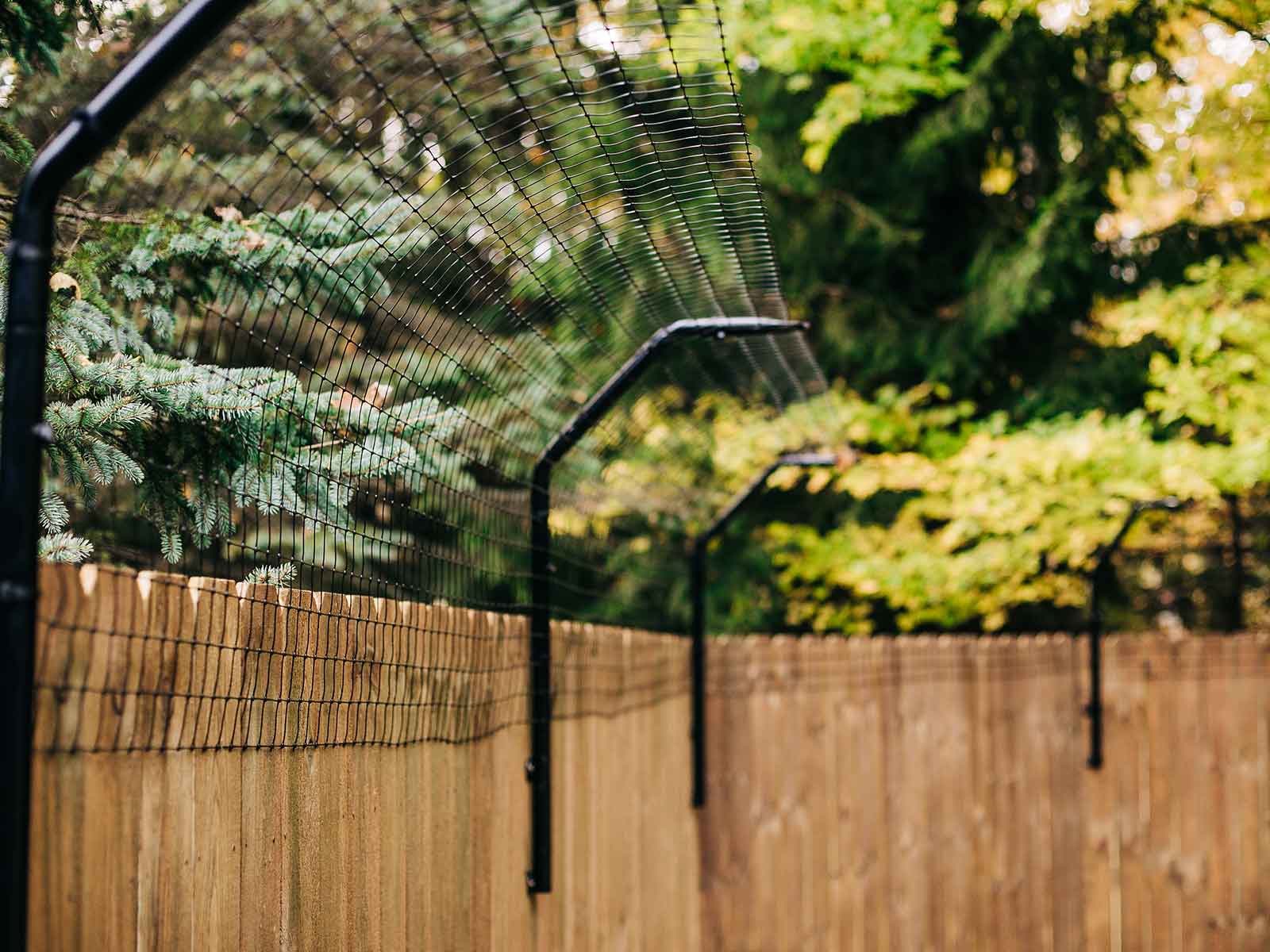 Dog Proofer Curved Houdini-Proof Fence Extensions On A Wood Fence