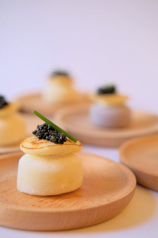 A plate of white sweet cream mochi with a blini garnish topped with black caviar.