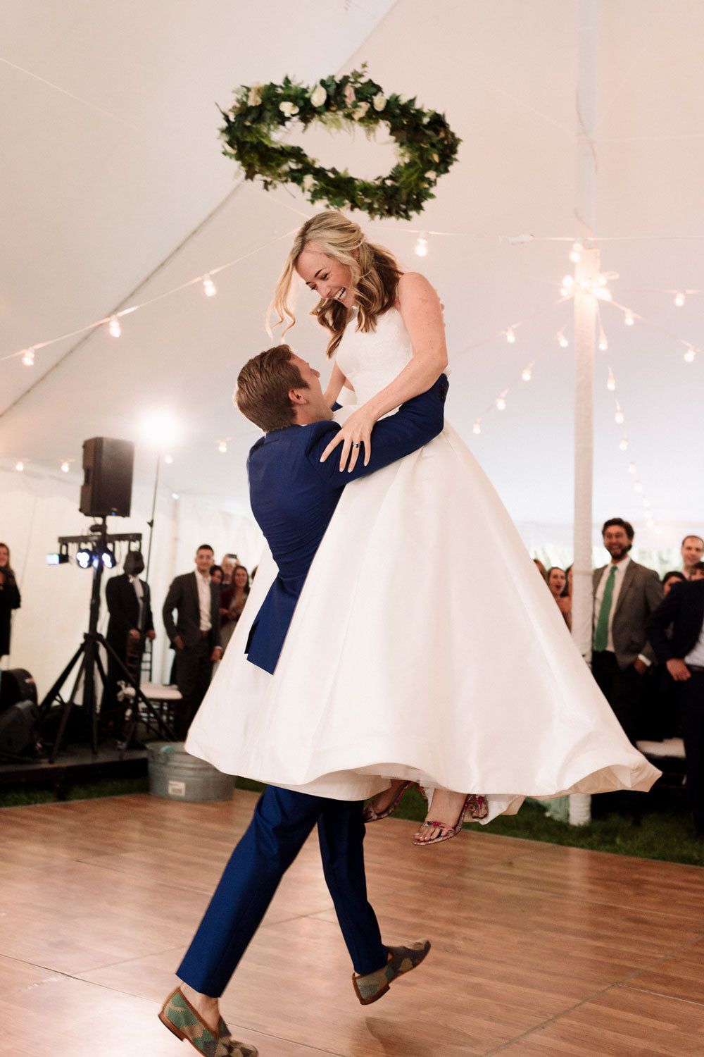 Alex Pardying wearing kilim shoes is lifting up Christina, his new wife, on dance floor at their wedding.