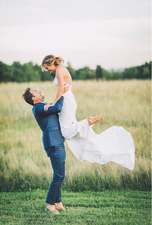 Nick holding up his bride in a field while wearing mens kilim loafers