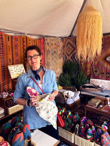 brimfield antique market customer with new womens velvet slides and womens kilim loafers surrounded by kilim carpets and mens kilim loafers.