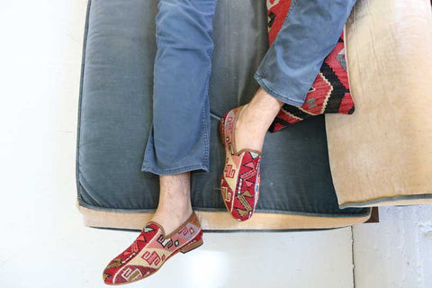 Mens kilim smoking shoes in sumak style on cousin with feet hanging off tan couch. 