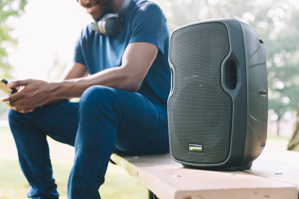 Man on a bench listening to music with his portable bluetooth speaker
