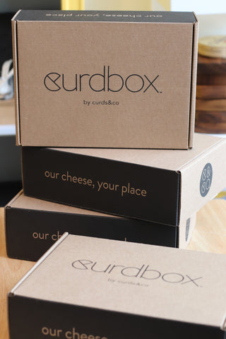A stack of curdbox boxes - our cheese and pairing subscriptiong bo