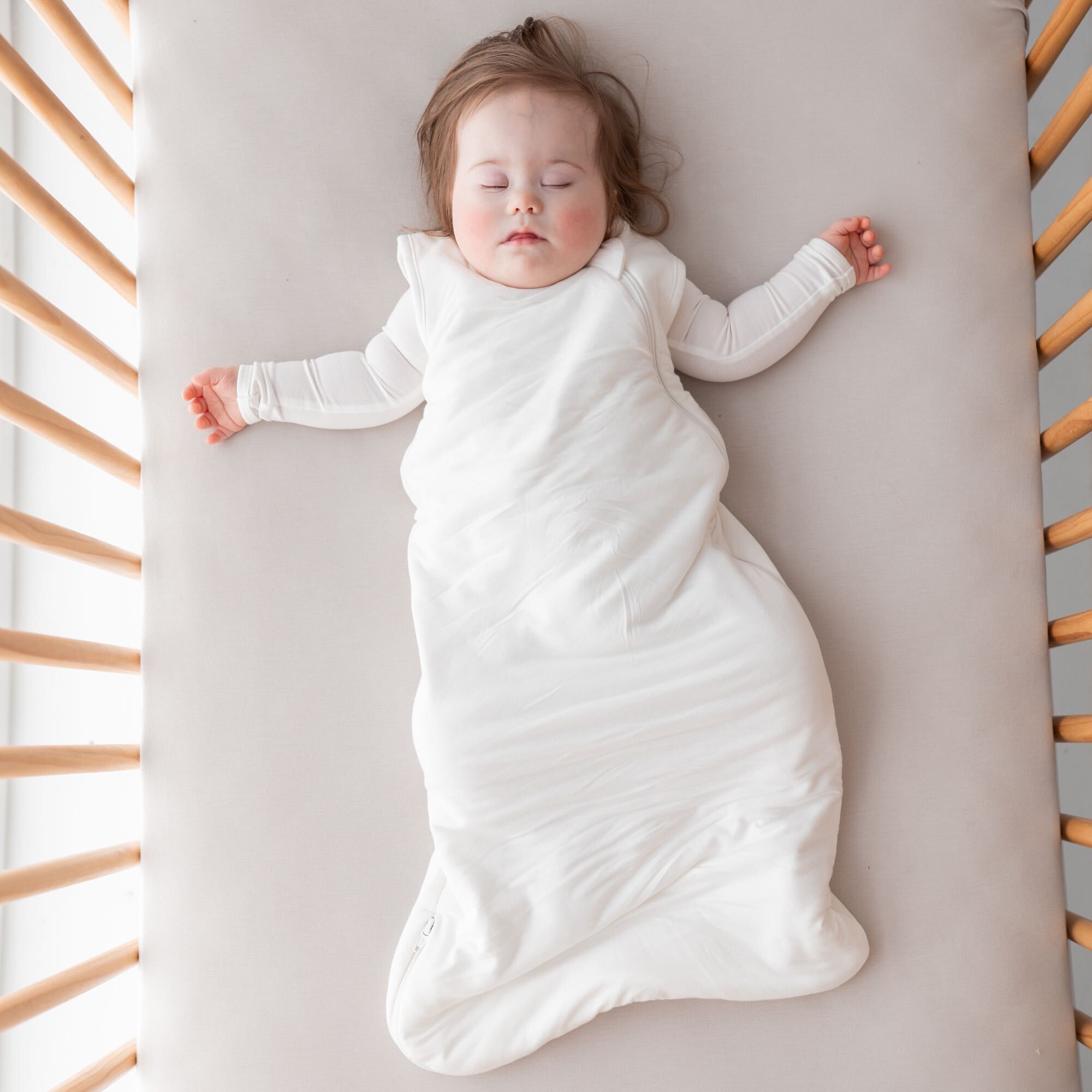 Baby asleep in a crib wearing a Kyte sleep bag