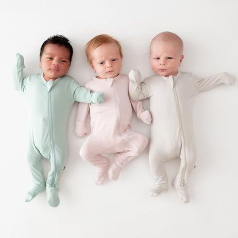 newborn babies laying next to each other wearing kyte baby preemie footies