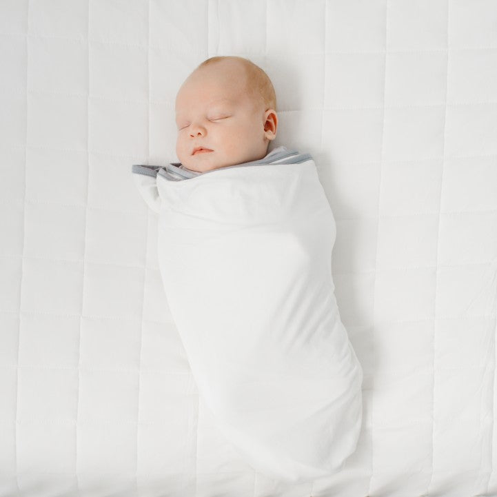 Baby being swaddled in white swaddle